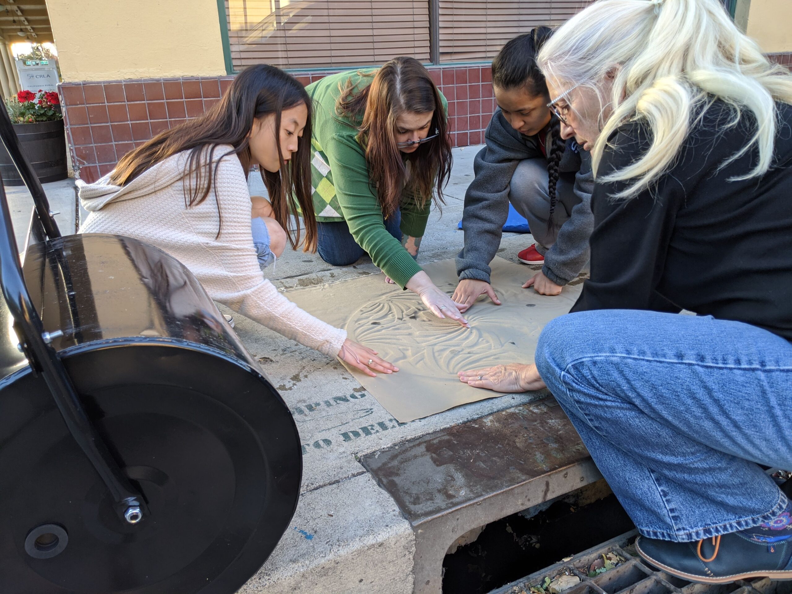 An image of Paula Sheil and a group of students doing manhole-cover art.